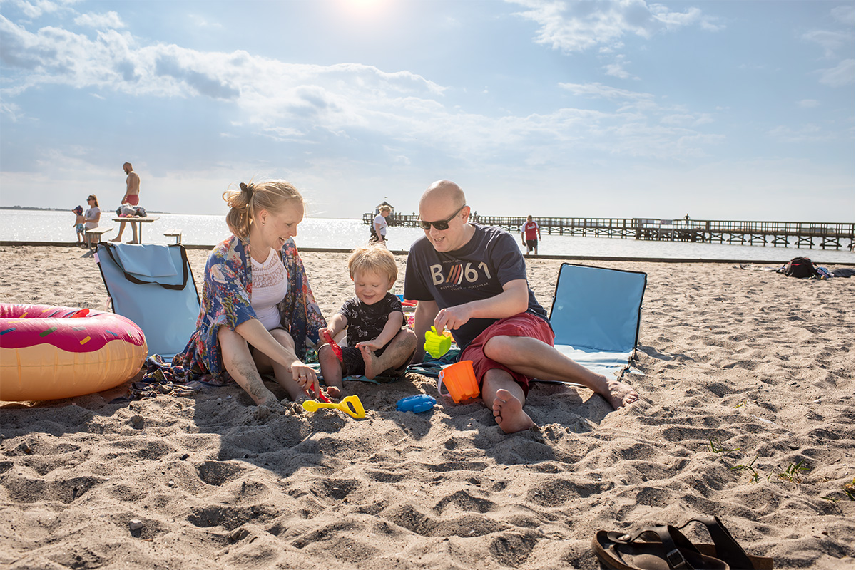 Mor, far og barn hygger sig på stranden